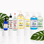 A lineup of eight Happy Hair hair care products on white cylindrical pedestals, with green monstera leaves in the foreground and background against a white studio backdrop.