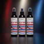 Three bottles of  Salon CandiesEdge Up Spray arranged side by side on a reflective dark surface, with red and blue spotlighting in the background.